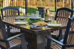 Rocket Outdoors metal patio dining table set with grilled ribs, pasta, wine, and candles for an autumn backyard meal.