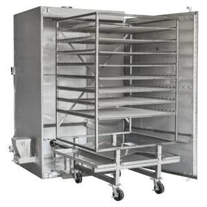 Angled view of a Rocket Outdoors roll-in gas smoker with door open, showing the wheeled rolling rack cart loaded into the cooking chamber.