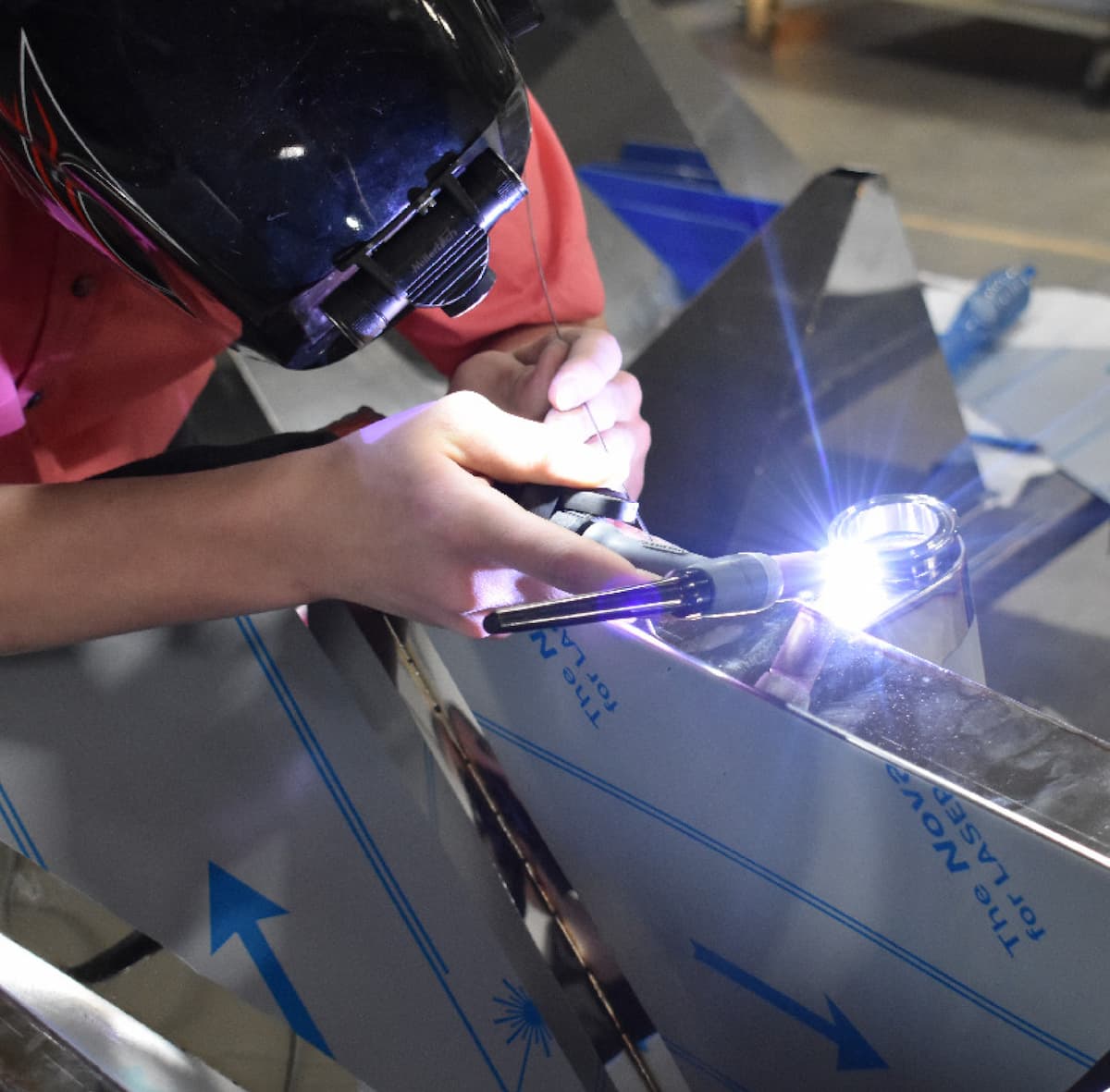 Welder fabricating a stainless steel Rocket Outdoors grill component during the manufacturing process.