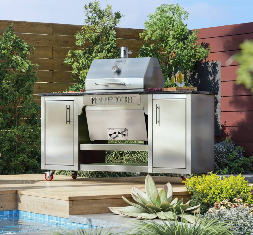 Silver Rocket stainless-steel grill cabinet on a wooden poolside deck surrounded by succulents, greenery, and a red accent wall.
