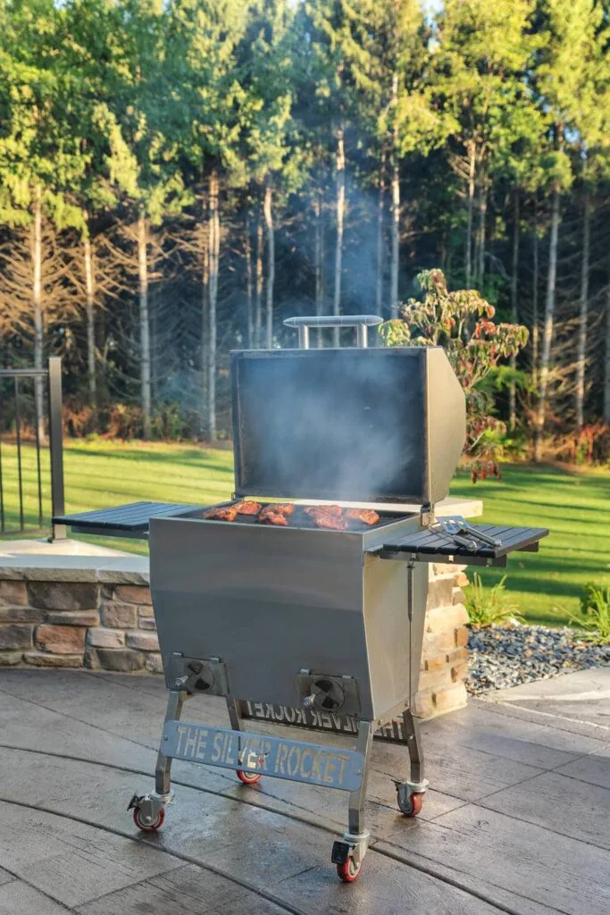 Silver Rocket Large Smoker Cooking Meat on Stone Patio