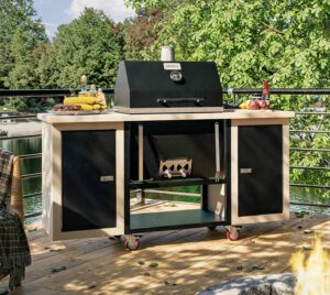 Sonic Rocket charcoal grill on a speckled pearl cart set up on a lakeside deck with grilled corn and peppers ready to cook.